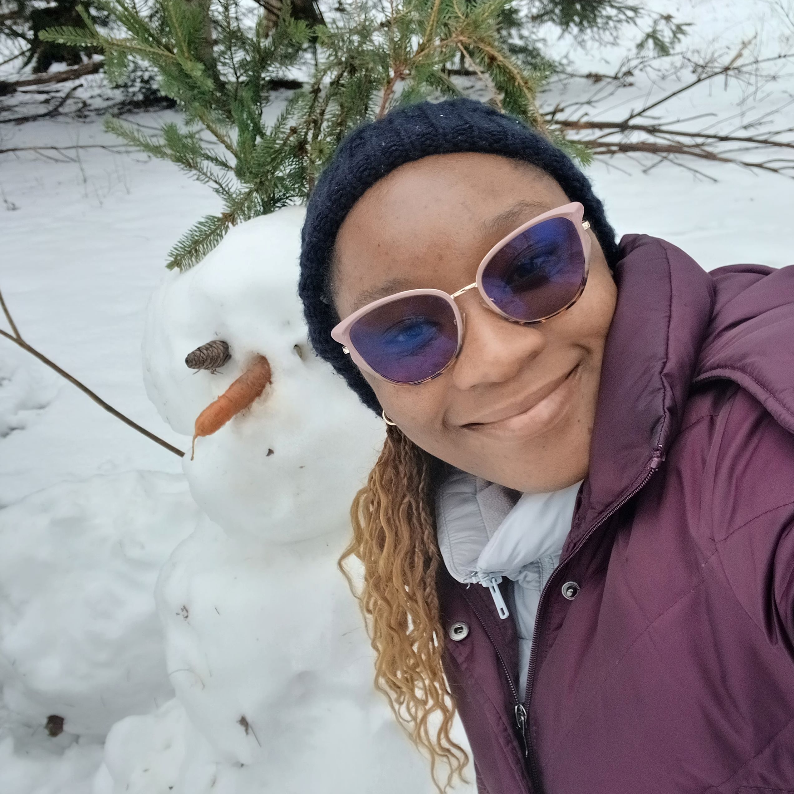 Girl sitting in snow next to snowman